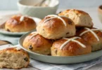 Traditional Easter Hot Cross Buns cooling on a wire rack in the kitchen.