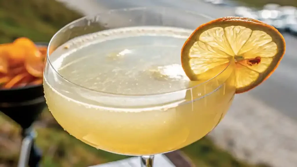 White lotus energy in a wide cylindrical glass with a thick base, delicate bubbles, and a dried lemon slice