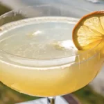 White lotus energy in a wide cylindrical glass with a thick base, delicate bubbles, and a dried lemon slice