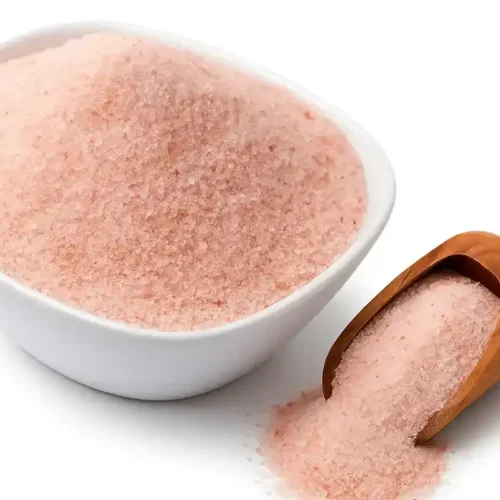 Preparing a Himalayan salt diet drink with pink salt and warm water in a clear glass