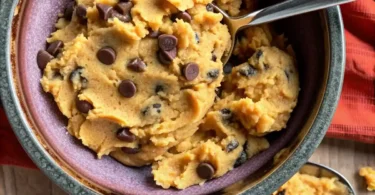 Overhead view of protein cookie dough recipe ingredients including almond flour, protein powder, and chocolate chips on a marble counter